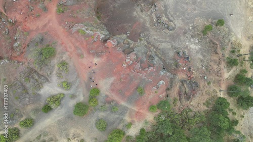 Red and brown rocky area with a few trees in the background