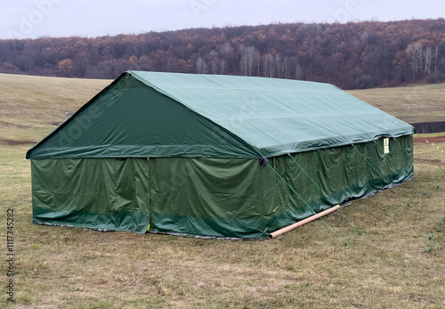 A large green tent is set up in a field