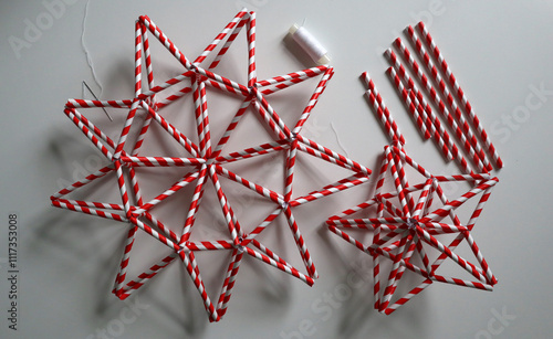 Set of handmade stars in red and white stripe. Different shape. Chaotically placed on white background. Needle, white thread, paper straws for drinks are nearby. Idea for decoration. Christmas. Photo. photo