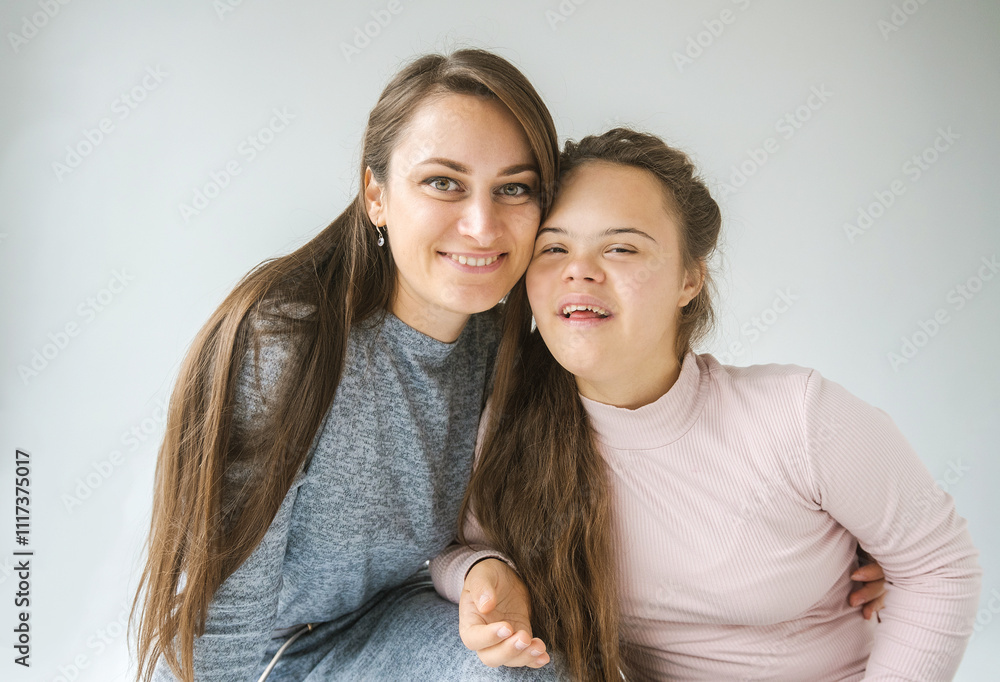 A close-up portrait of a happy mother and daughter, the daughter having Down syndrome, smiling warmly at the camera A close-up portrait of a happy mother and daughter, the daughter having Down syndrome, smiling warmly at the camera