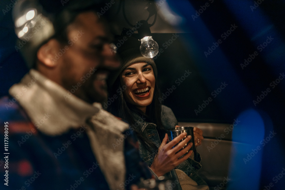 Obraz premium Cozy couple in a car trunk talking and sipping hot beverages on a chilly evening