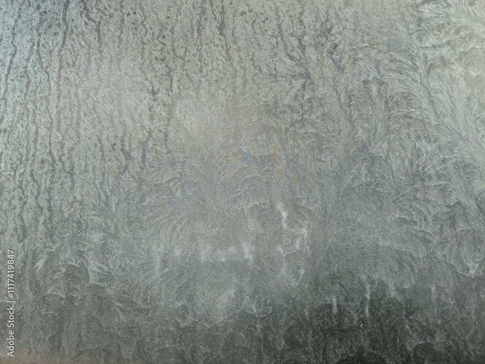 A grey wall with a frosted glass window. The window is covered in a thin layer of ice. A grey wall with a frosted glass window. The window is covered in a thin layer of ice.