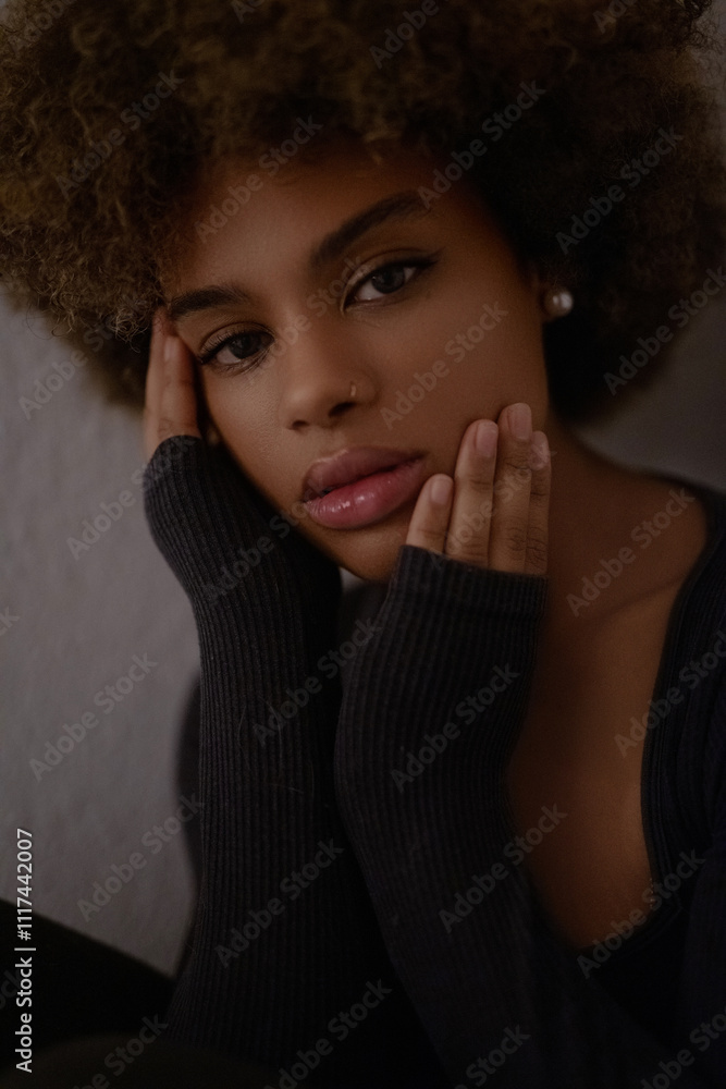 a close-up portrait of a person with curly hair, wearing a black top and an earring, in a dark and moody setting a close-up portrait of a person with curly hair, wearing a black top and an earring, in a dark and moody setting