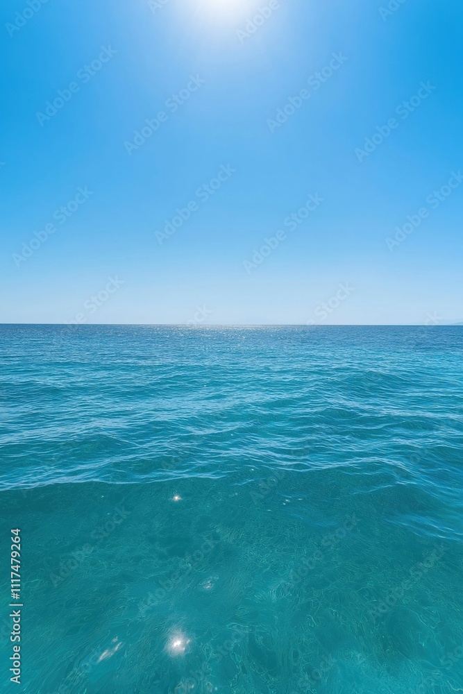 Obraz premium The ocean is calm and clear, with a bright blue sky above. The water is a deep shade of blue, and the sun is shining brightly, creating a peaceful and serene atmosphere