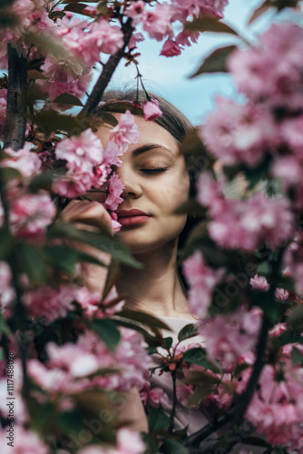 A girl in the park, around her, flowers look like sakura, creating an atmosphere of spring and tranquility. photo