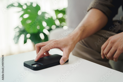 Close up of a man's hand is to put his mobile phone on the table after stopping using it.