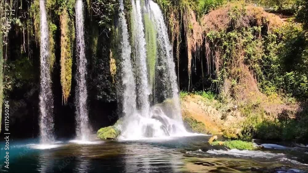 A beautiful waterfall with clear water falling into a blue lake in a picturesque forest place A beautiful waterfall with clear water falling into a blue lake in a picturesque forest place