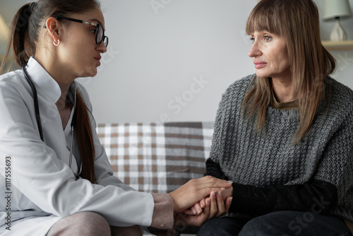 doctor holding patient's hands to reassure patient, health examination while sitting together on couch at home