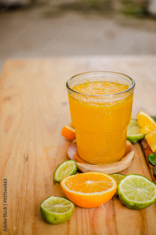 A glass of freshly squeezed orange juice on a wooden table surrounded by orange slices and orange leaves A glass of freshly squeezed orange juice on a wooden table surrounded by orange slices and orange leaves