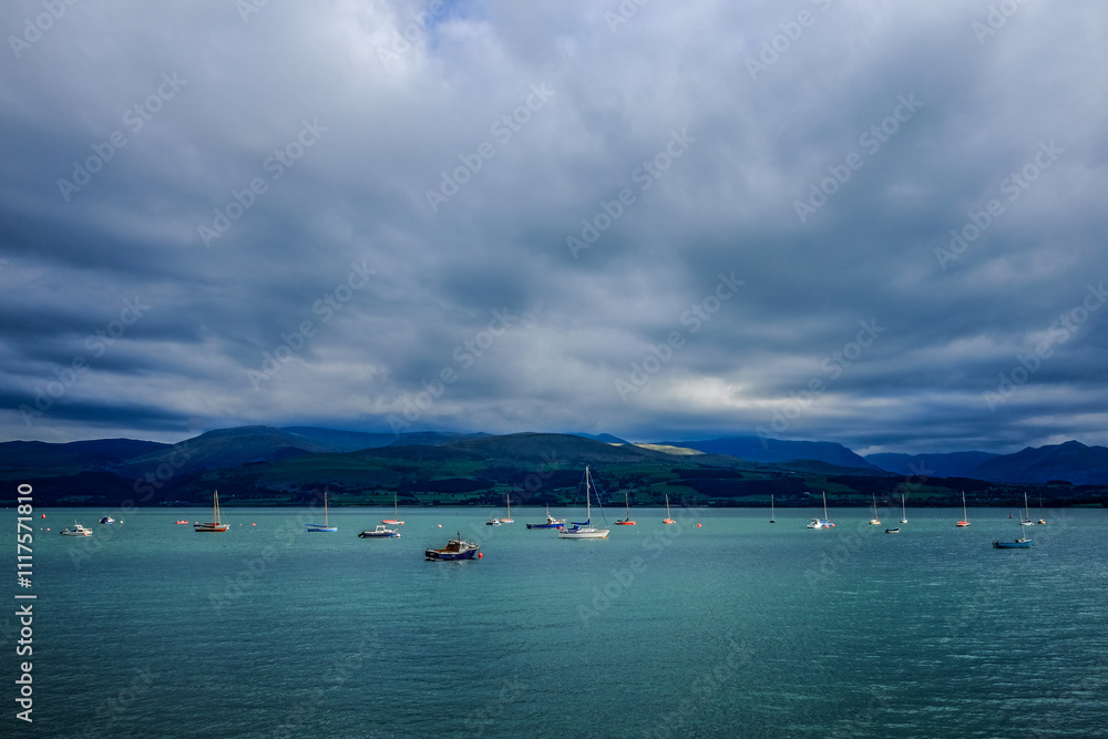 Obraz premium Boats at anchor on Menai Straits with moody sky