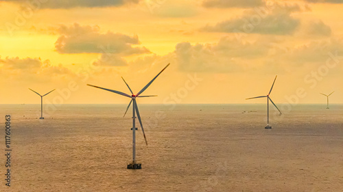 Tall windmill turbines against a clear blue sky, generating renewable energy in the serene Go Cong, Vietnam landscape by the sea. Like windmill park Westermeerdijk in the Noordoostpolder Netherlands.