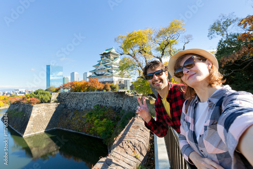 A young travel couple takes a selfie at Osaka Castle, Osaka Castle is one of the most famous landmarks in Japan and Osaka, vacation lifestyle.