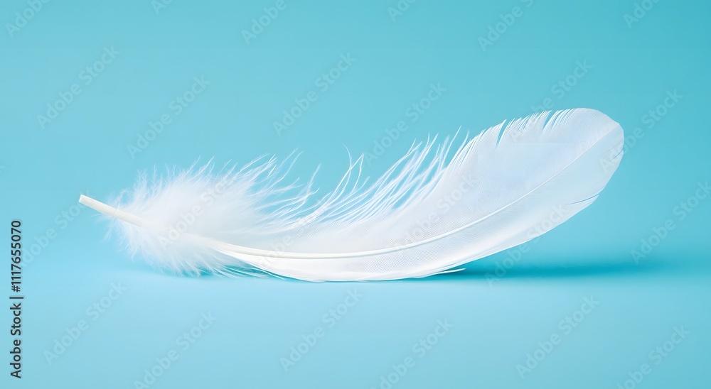 Obraz premium A single floating white feather floats in the air against a light blue background, highlighting the softness of the feather. Representing a feeling of calm and tranquility. It looks very beautiful.