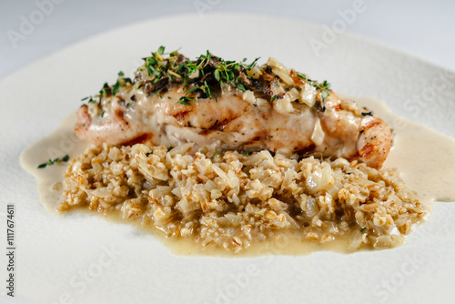 checken roll with mushroom white creamy sauce served on white plate and background, topped with herbs garnished with porridge