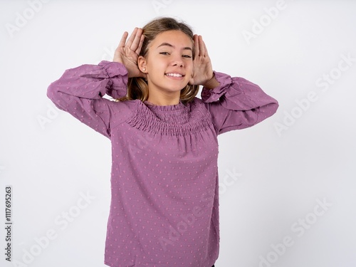 Beautiful teenager girl wearing purple T-shirt Trying to hear both hands on ear gesture, curious for gossip. Hearing problem, deaf