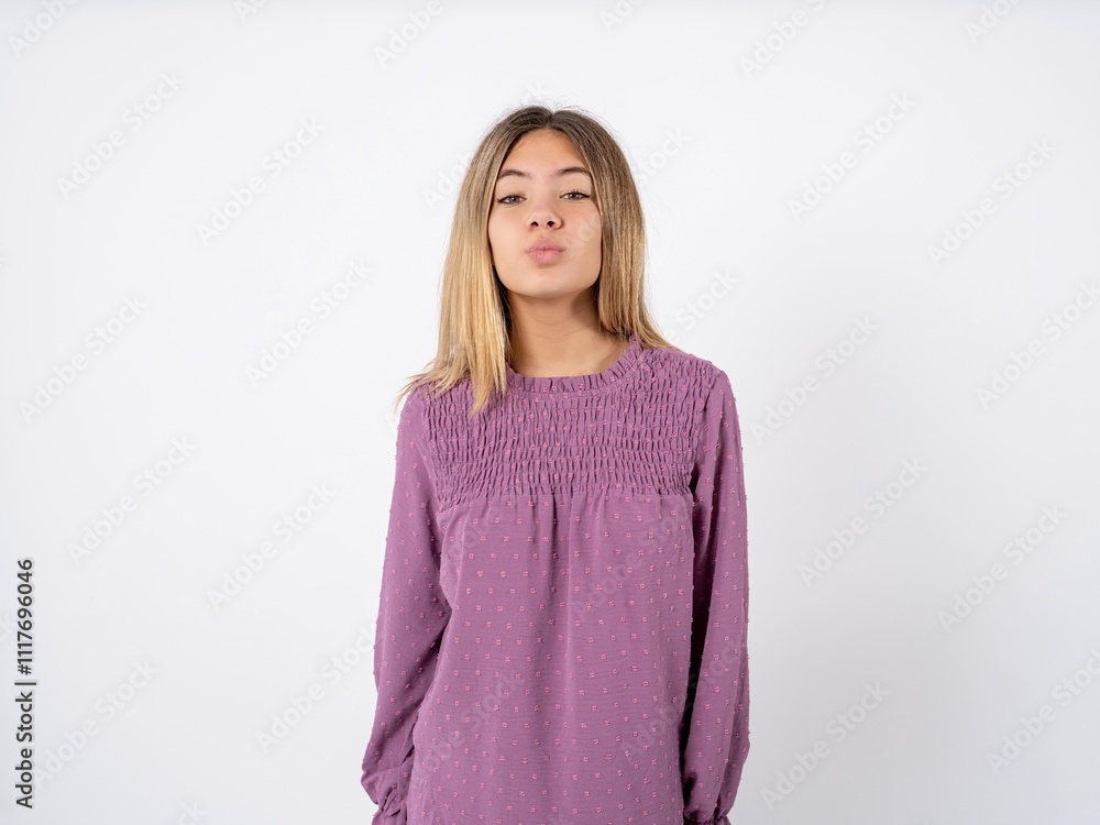 Shot of pleasant looking Beautiful teenager girl wearing purple T-shirt , pouts lips, looks at camera, Human facial expressions Shot of pleasant looking Beautiful teenager girl wearing purple T-shirt , pouts lips, looks at camera, Human facial expressions