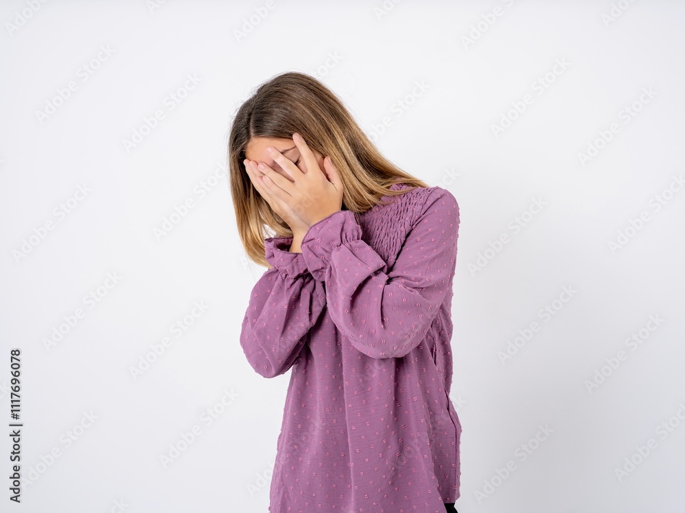 Sad Beautiful teenager girl wearing purple T-shirt crying covering her face with her hands. Sad Beautiful teenager girl wearing purple T-shirt crying covering her face with her hands.