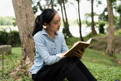 Young Professional Reading and Working Outdoors in a Serene Park Setting with Natural Light and Greenery photo