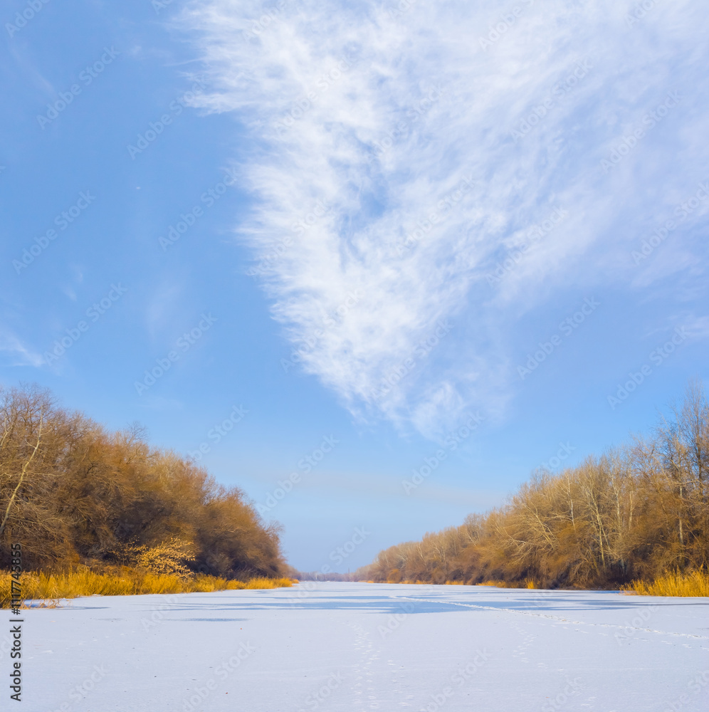 winter frozen river covered by snow with forest on coast under blue cloudy sky winter frozen river covered by snow with forest on coast under blue cloudy sky