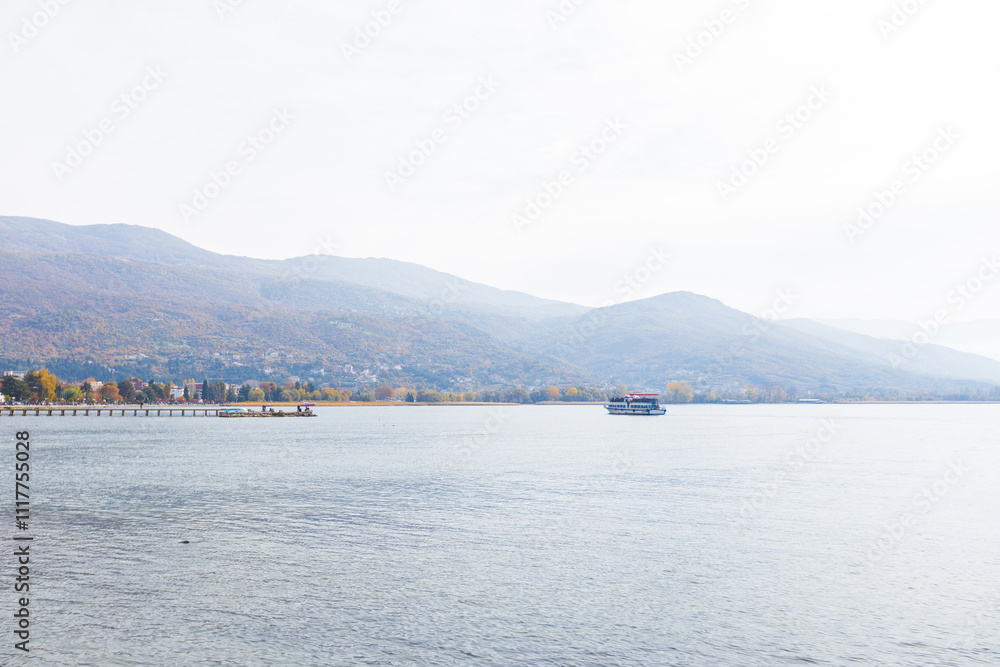 Peaceful autumn morning at Lake Ohrid with calm waters, muted colors, and distant view of charming Ohrid town. Peaceful autumn morning at Lake Ohrid with calm waters, muted colors, and distant view of charming Ohrid town.