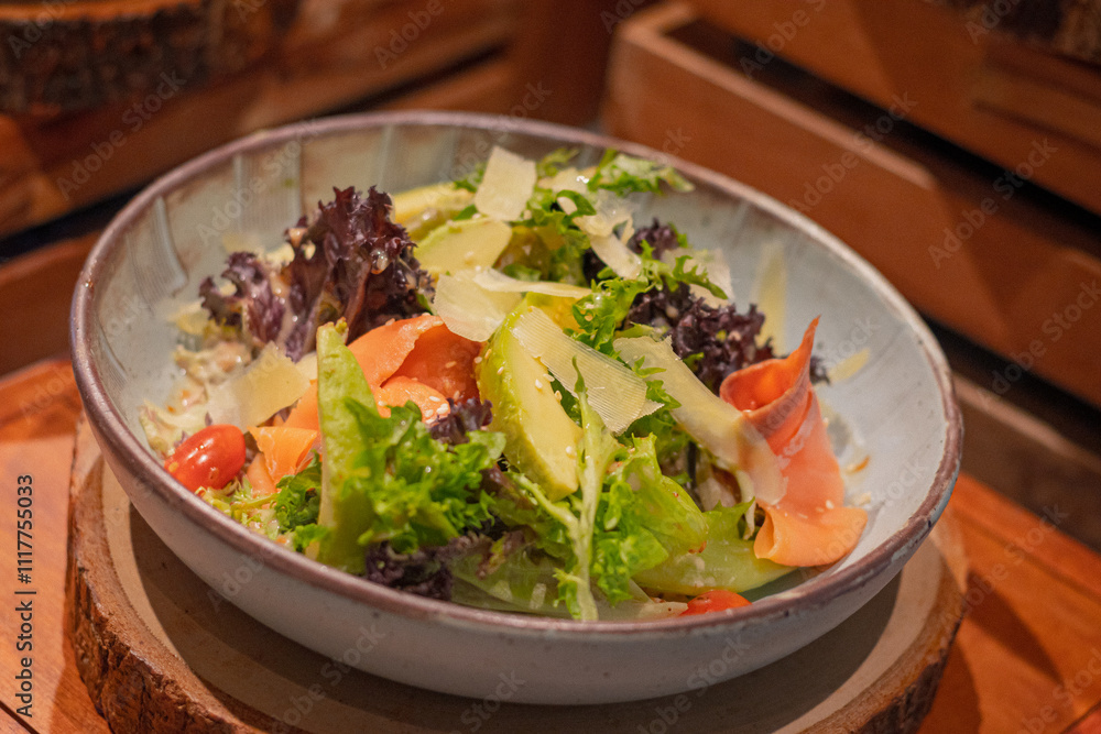 Rocket salad, include smoked salmon, avocado, lettuce, tomato and italian sauce on bowl, place on wooden serving board Rocket salad, include smoked salmon, avocado, lettuce, tomato and italian sauce on bowl, place on wooden serving board