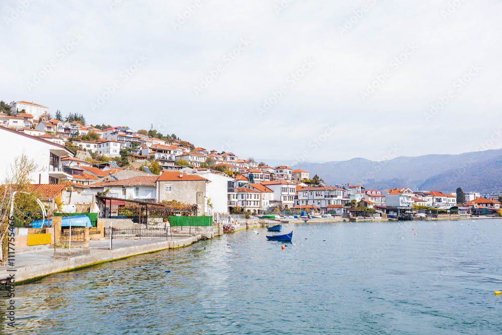 Charming Ohrid town with cascading colorful houses, calm Lake Ohrid waters, and a clear blue sky reflection. Charming Ohrid town with cascading colorful houses, calm Lake Ohrid waters, and a clear blue sky reflection.