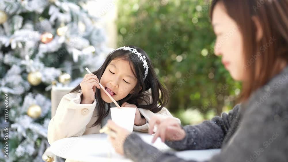 At a lovely Christmas-themed cafe in downtown Shanghai, China, a Singaporean woman in her 40s looks at her smartphone while her 9-year-old daughter drinks hot chocolate next to her. slow motion. At a lovely Christmas-themed cafe in downtown Shanghai, China, a Singaporean woman in her 40s looks at her smartphone while her 9-year-old daughter drinks hot chocolate next to her. slow motion.