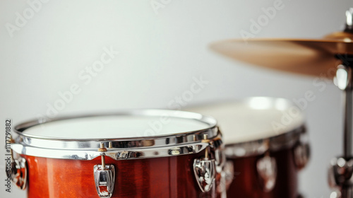 Close-up view of a polished drum set with a focus on the shiny tom-tom and cymbal in a minimalistic setting. photo