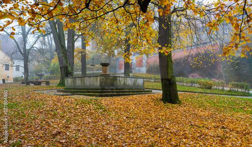Obraz na płótnie A beautiful autumn scene of the fountain in front of Cesky Krumlov Castle, surrounded by trees with golden leaves, blending nature and historic architecture in a serene atmosphere w salonie