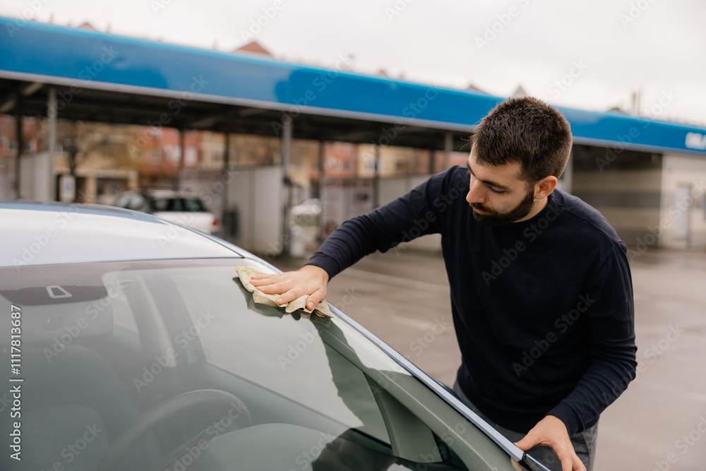 Man thoroughly wiping down the car’s windshield outdoors.
Man thoroughly wiping down the car’s windshield outdoors.
