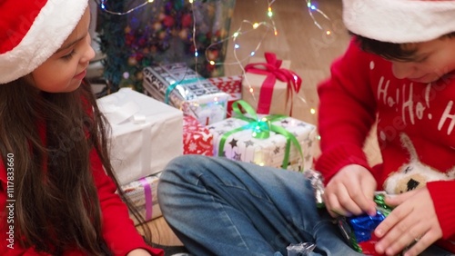 Happy Little Family Exchanging Gifts on Christmas Eve: Brother and Sister Receiving their Gifts. Happy Children Getting New Toys from Mom and Dad, with Family. children enjoy christmas and new year