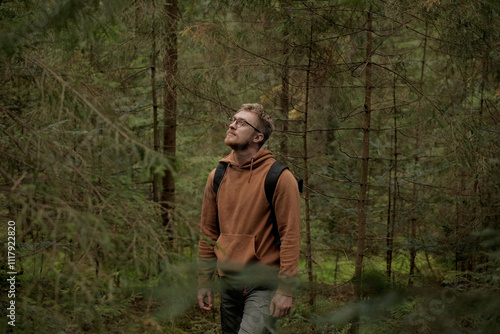 Autumn walk in coniferous forest, man with glasses