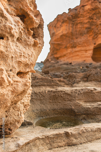 Stunning Natural Rock Formation in Rugged Desert Landscape Showcasing Unique Erosion Patterns and Warm Earth Tones Underneath a Subtle Clear Sky, Capturing the Beauty of Nature's Geological Wonders