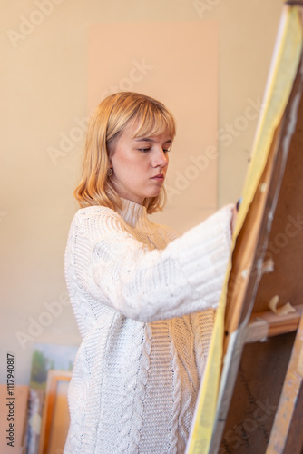 Young female artist painting on easel in studio. Art concept. A woman draws.