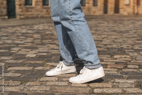 Casual style with white sneakers and jeans on cobblestone street in urban setting