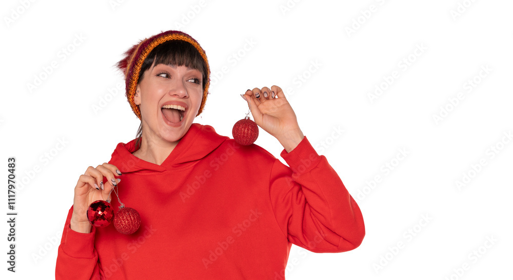 Cheerful woman wearing a red hoodie and colorful beanie holds Christmas ornaments while celebrating the holiday spirit Cheerful woman wearing a red hoodie and colorful beanie holds Christmas ornaments while celebrating the holiday spirit