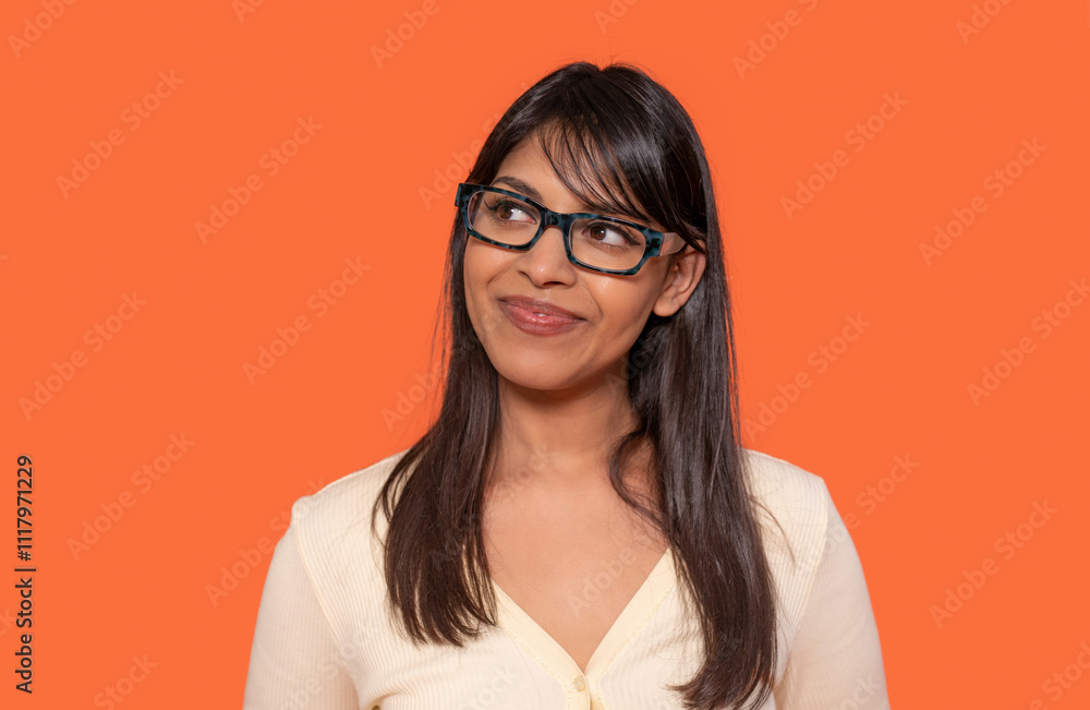 Smiling woman with glasses poses against bright orange background, showcasing confidence and style Smiling woman with glasses poses against bright orange background, showcasing confidence and style