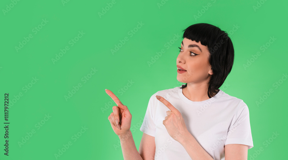 Young woman gesturing towards two directions against a green background in a casual setting Young woman gesturing towards two directions against a green background in a casual setting