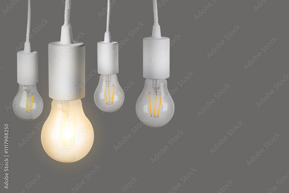 One glowing light bulb among others on grey background One glowing light bulb among others on grey background