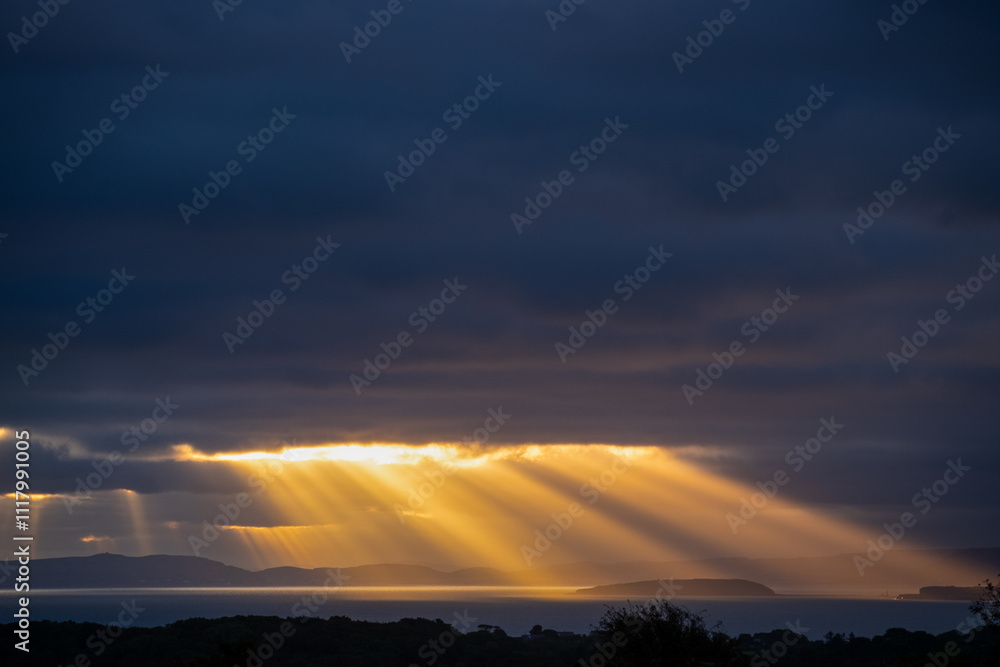 Spectacular sun rays over coast from distance