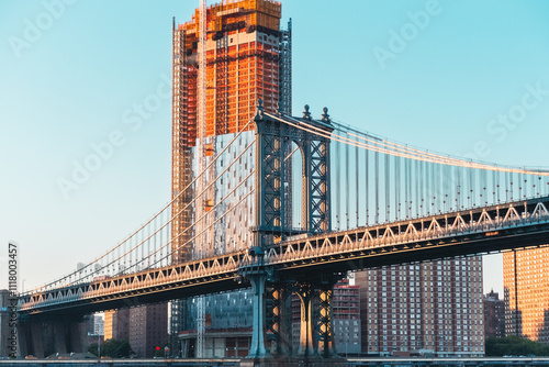 View of Manhattan Bridge at Sunset with Skyscraper Under Construction in New York City, Capturing Urban Architecture and Cityscape in Warm Evening Light