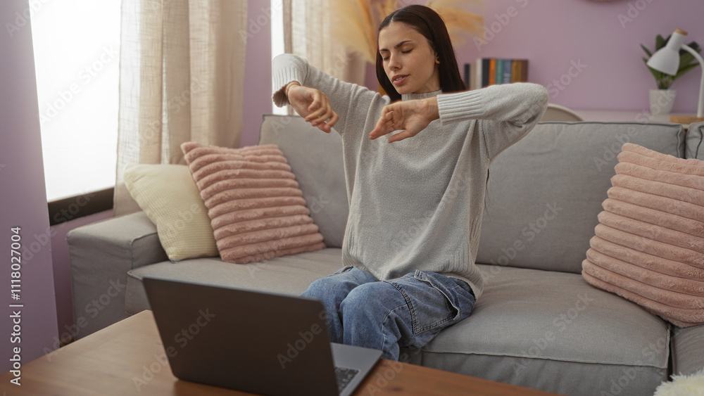 Woman stretching indoors while sitting on a comfortable couch in a cozy living room, showcasing an everyday relaxed atmosphere with a laptop in front. Woman stretching indoors while sitting on a comfortable couch in a cozy living room, showcasing an everyday relaxed atmosphere with a laptop in front.