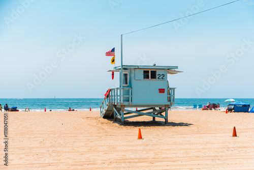 Sunny Day at the Beach with a Lifeguard Tower Overlooking the Ocean and Visitors Relaxing in the Sand, Under the Bright Blue Sky photo