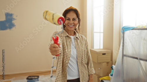 Photography Woman painting with roller in new apartment, smiling in renovated living space