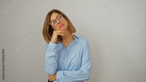 Woman thinking on an isolated white background, wearing a blue shirt and glasses, with a pensive expression, blonde hair, young adult, caucasian, and attractive