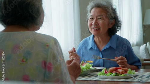 Group of Joyful senior women with gray hair having breakfast together at home. Elderly retired woman friends enjoying a plate of food, exuding warmth and contentment. Enjoy the retirement life concept