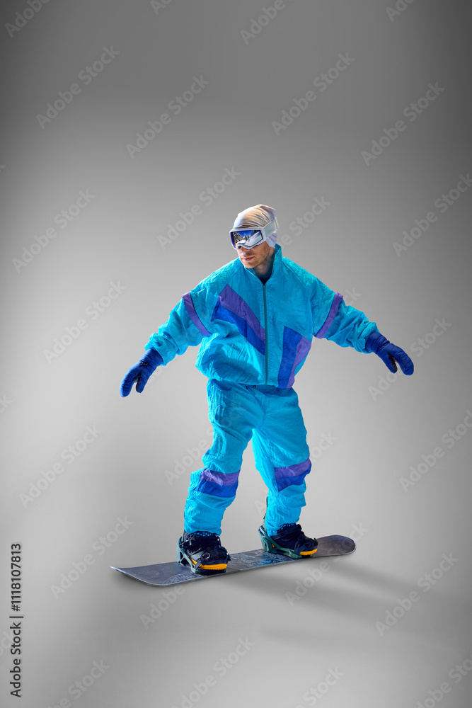 Snowboarder balancing skillfully during snowboarding session, against grey studio background, symbolizing adventure and athletic precision. Concept of extreme sport, energy, speed, fashion. Snowboarder balancing skillfully during snowboarding session, against grey studio background, symbolizing adventure and athletic precision. Concept of extreme sport, energy, speed, fashion.