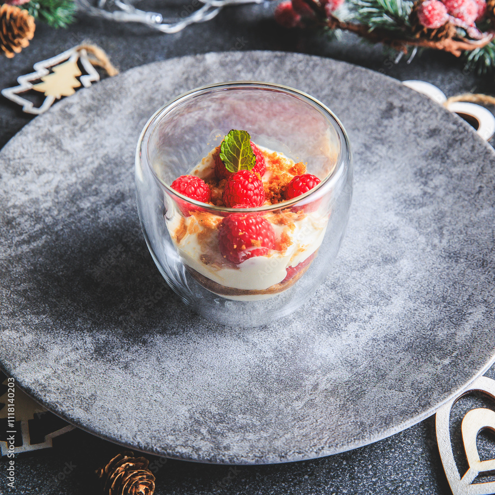 Verrine of crushed speculoos, mascarpone and raspberries on a gray background decorated for Christmas