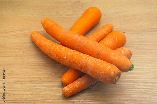 Fresh carrots on a wooden kitchen countertop, vibrant orange hues, arranged neatly in a rustic kitchen setting with soft indoor lighting. photo