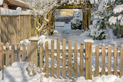 Wooden fence and gate of residential area entrance on bright winter day photo